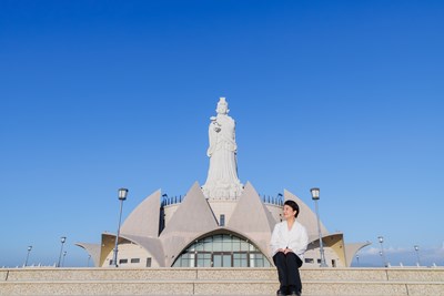 盧市長愜意地坐在大步梯上，襯托出了媽祖雕像的巨大
