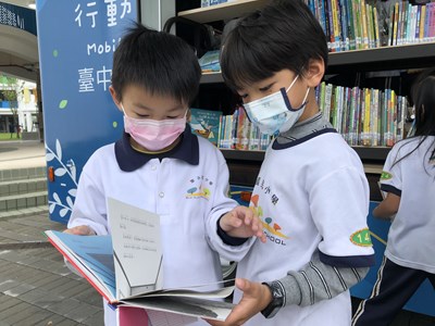 學童在書車前開心翻閱圖書